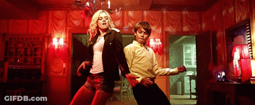 A Man And A Woman Are Dancing In A Room With Red Walls . GIF