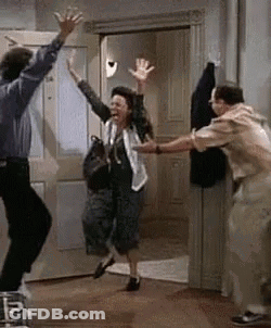 A Man And A Woman Are Dancing In A Room With Their Hands In The Air . GIF