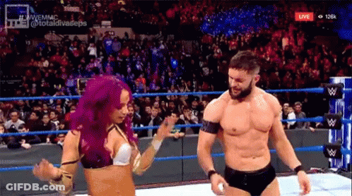 A Man And A Woman Are Dancing In A Wrestling Ring While A Crowd Watches . GIF