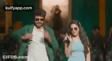 A Man And A Woman Are Dancing In Front Of A Crowd . GIF