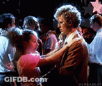 A Man And A Woman Are Dancing In Front Of A Crowd Of People . GIF