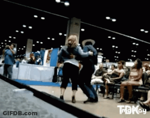 A Man And A Woman Are Dancing In Front Of A Crowd That Is Watching .. GIF