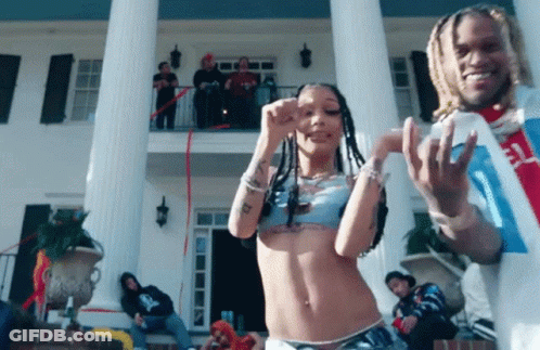 A Man And A Woman Are Dancing In Front Of A Large Building GIF