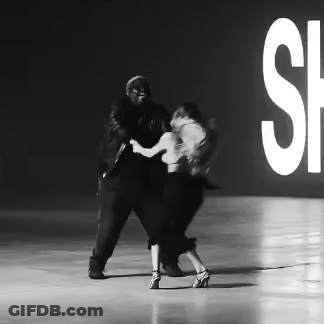 A Man And A Woman Are Dancing In Front Of A Large S GIF