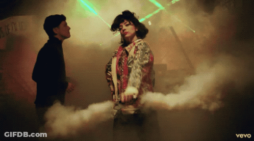 A Man And A Woman Are Dancing In Front Of A Sign That Says ' Vevo ' GIF