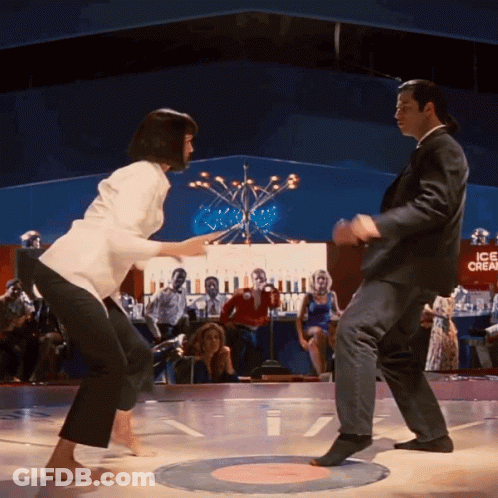 A Man And A Woman Are Dancing On A Dance Floor In Front Of A Sign That Says Ice Cream GIF