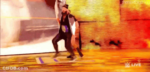 A Man And A Woman Are Dancing On A Stage In Front Of A Wall . GIF