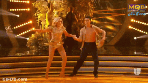 A Man And A Woman Are Dancing On A Stage With A Mqb Logo In The Background GIF