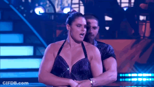 A Man And A Woman Are Dancing On A Stage With Purple Lights GIF