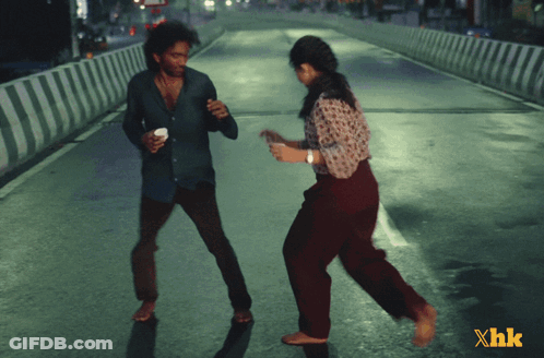 A Man And A Woman Are Dancing On A Street With Xhk Written In The Corner GIF