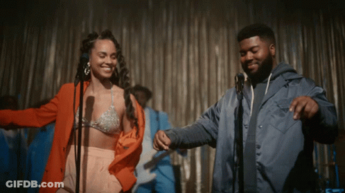 A Man And A Woman Are Dancing On Stage In Front Of A Microphone GIF