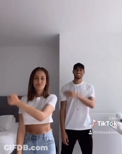 A Man And A Woman Are Dancing Together In A Bedroom . The Woman Is Wearing A Crop Top . GIF