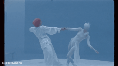 A Man And A Woman Are Dancing Together In A Blue Room GIF
