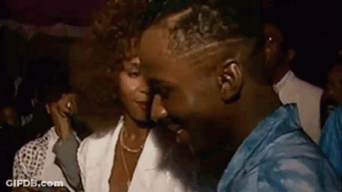 A Man And A Woman Are Dancing Together In A Crowd Of People At A Party . GIF