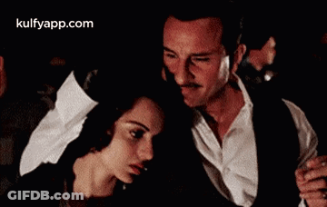 A Man And A Woman Are Dancing Together In A Dark Room In A Movie . GIF