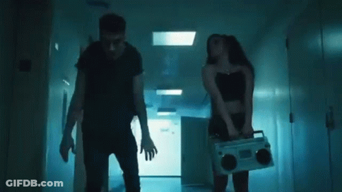 A Man And A Woman Are Dancing Together In A Hallway In A Dark Room . GIF