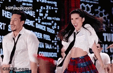 A Man And A Woman Are Dancing Together On A Stage In Front Of A Large Screen . GIF