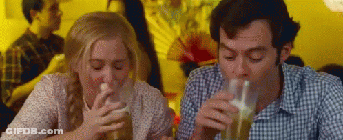 A Man And A Woman Are Drinking Beer From Glasses While Sitting At A Table . GIF