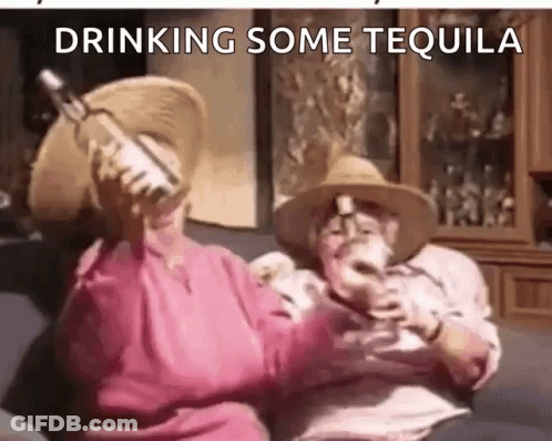 A Man And A Woman Are Drinking Tequila On A Couch . GIF