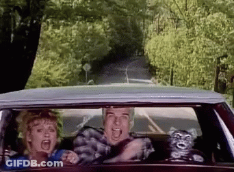 A Man And A Woman Are Driving Down A Road In A Car GIF