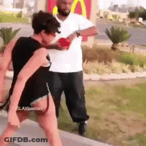 A Man And A Woman Are Fighting In Front Of A Mcdonald 'S . GIF