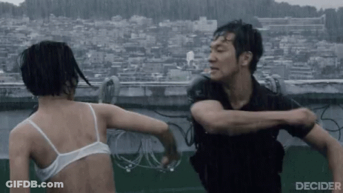 A Man And A Woman Are Fighting In The Rain . The Woman Is Wearing A White Bra . GIF