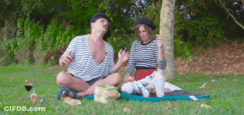 A Man And A Woman Are Having A Picnic With Their Dog GIF