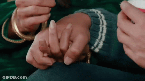A Man And A Woman Are Holding Hands And The Woman Is Wearing A Ring On Her Finger . GIF