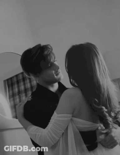 A Man And A Woman Are Hugging And Looking At Each Other In A Black And White Photo . GIF