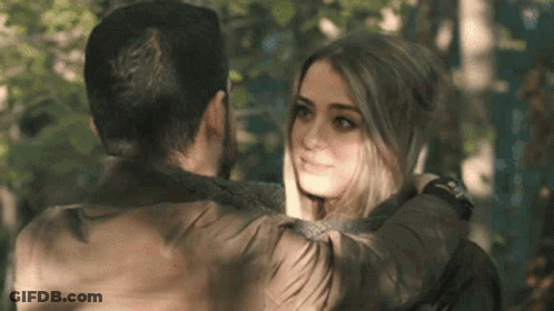 A Man And A Woman Are Hugging And Looking At Each Other In The Woods . GIF