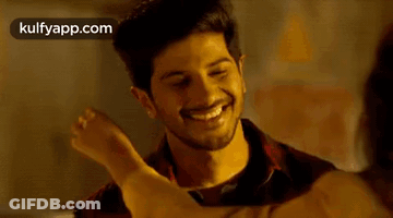 A Man And A Woman Are Hugging Each Other And Smiling . The Woman Is Wearing A Yellow Shirt . GIF