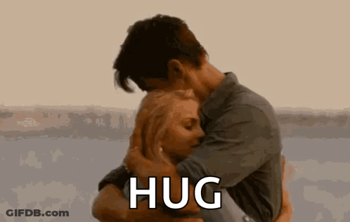A Man And A Woman Are Hugging Each Other And The Man Is Saying `` Hug '' . GIF