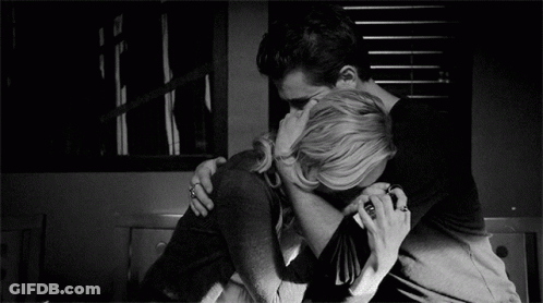 A Man And A Woman Are Hugging Each Other In A Black And White Photo GIF
