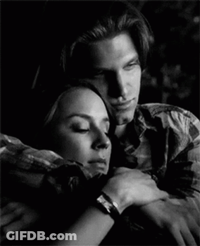 A Man And A Woman Are Hugging Each Other In A Black And White Photo GIF
