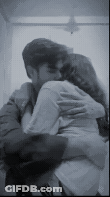 A Man And A Woman Are Hugging Each Other In A Black And White Photo GIF