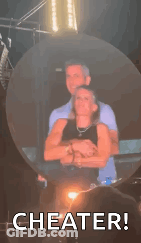 A Man And A Woman Are Hugging Each Other In A Bubble With The Words `` Cheater '' Written On It . GIF