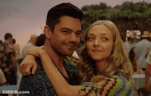 A Man And A Woman Are Hugging Each Other In A Crowded Area . GIF