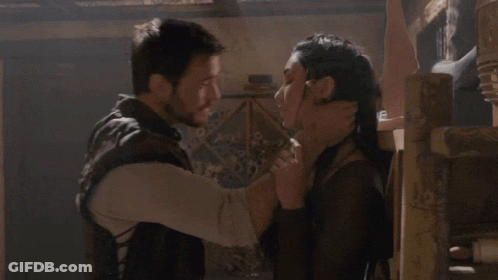 A Man And A Woman Are Hugging Each Other In A Dark Room GIF