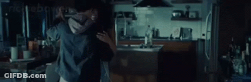 A Man And A Woman Are Hugging Each Other In A Kitchen . GIF