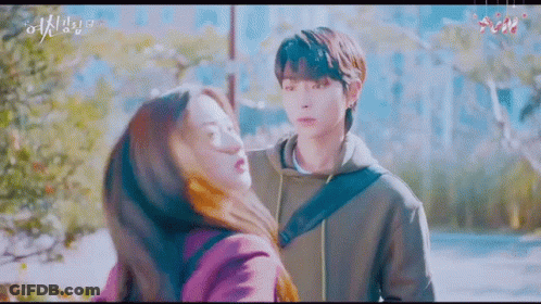 A Man And A Woman Are Hugging Each Other In A Park . GIF