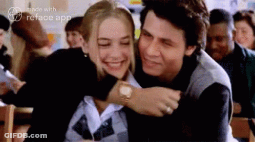 A Man And A Woman Are Hugging Each Other In A Room . GIF