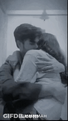 A Man And A Woman Are Hugging Each Other In A Room . GIF
