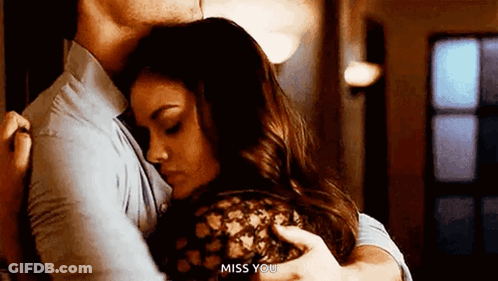 A Man And A Woman Are Hugging Each Other In A Room . GIF