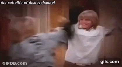 A Man And A Woman Are Hugging Each Other In A Room With Their Arms Outstretched . GIF