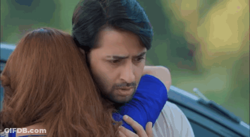 A Man And A Woman Are Hugging Each Other In Front Of A Car . GIF