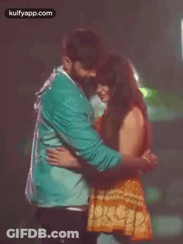 A Man And A Woman Are Hugging Each Other In The Dark . GIF