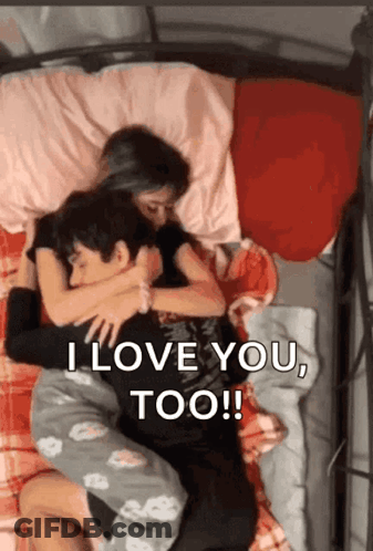 A Man And A Woman Are Hugging Each Other On A Bed And The Man Is Saying I Love You Too . GIF