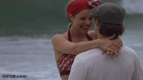 A Man And A Woman Are Hugging Each Other On The Beach GIF