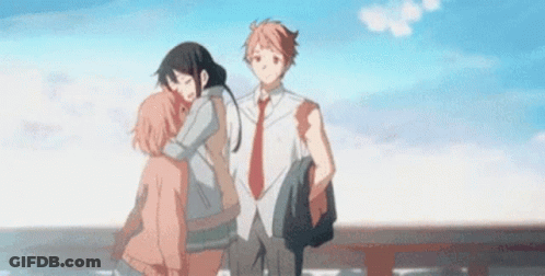 A Man And A Woman Are Hugging Each Other While Standing Next To Each Other On A Bridge . GIF