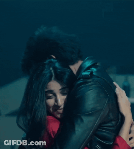 A Man And A Woman Are Hugging In A Dark Room GIF